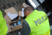 Policjant fotografuje kartony zabezpieczonych papierosów
