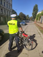 policjant stoi z rowerem na ulicy