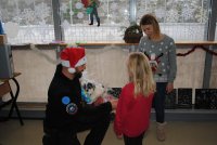 Paweł jest na misji w Kosowie podczas Świąt Bożego Narodzenia. Daje prezenty ubrany w czapkę Świętego Mikołaja dziewczynce, obok stoi opiekunka.