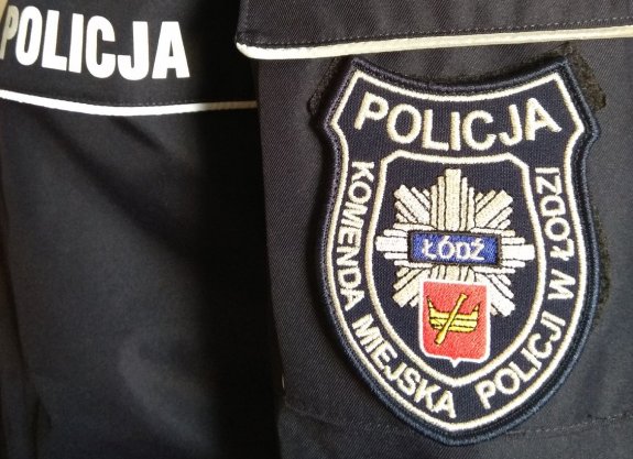 Napis POLICJA na mundurze obok naszywka z napisem Komenda Miejska Policji w Łodzi, gwiazdą policyjną w środku i na niej herb Łodzi