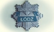 Na zdjęciu widzimy szarą gwiazdę policyjną , na której w górnej części jest umieszczony napis Policja, natomiast po środku jest umieszczony napis Łódź, który jest napisany dużymi literami.