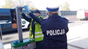 Umundurowany policjant ruchu drogowego wraz z funkcjonariuszem Inspekcji Transportu Drogowego sprawdzają ustawienie świateł