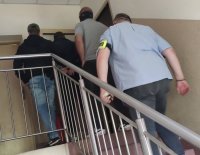 Policjanci wprowadzają mężczyznę po schodach do pomieszczeń w II komisariacie Policji Komendy Miejskiej Policji w Łodzi.