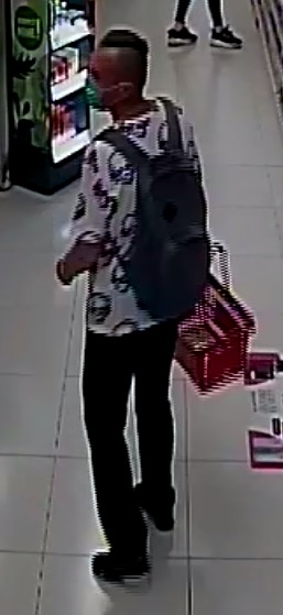 Na zdjęciu sprawca kradzieży sklepowej - młody mężczyzna ubrany w jasny t-shirt z nadrukiem, ciemnie długie spodnie, maseczka na twarzy, plecak