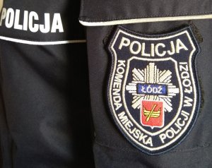 Napis POLICJA na mundurze oraz naszywka z logo Łodzi i napisem Komenda Miejska Policji w Łodzi