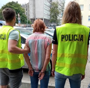 Policjanci konwojują zatrzymaną kobietę