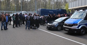 Radiowozoy policyjne obok, których przechodzą kibice. Zdjęcie wykonane przy stadionie klubu.
