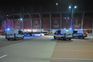 Radiowozy policyjne zaparkowane przed stadionem Widzewa Łódź.