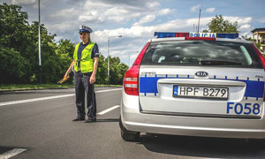 policjant w mundurze stoi na drodze przy radiowozie