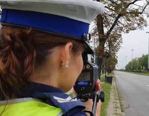 Policjantka mierzy urządzeniem specjalistycznym prędkość pojazdów