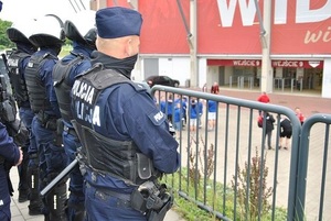 Funkcjonariusze oddziału prewencji w Łodzi obserwujący kibiców drużyn spotkania piłkarskiego.