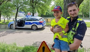 Policjant z dzieckiem uczestniczącym w festynie