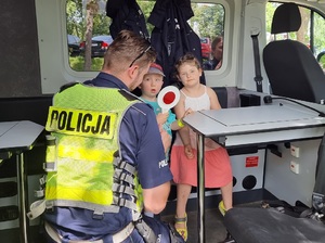Policjant prezentuje dzieciom specjalistyczny radiowóz