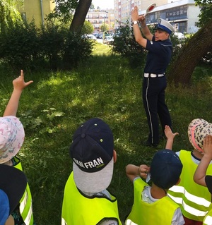 Policjantka wraz z dziećmi podczas spotkania, na którym tłumaczy jak bezpiecznie korzystać z drogi.