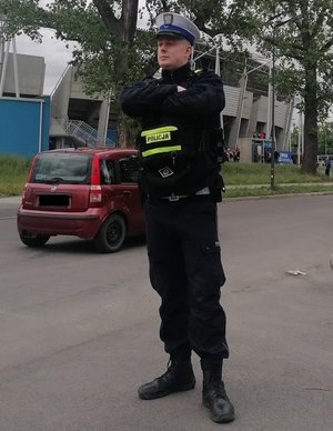 Policjant podczas służby, stoi w rejonie jezdni.