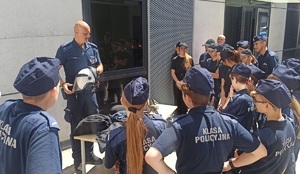 Policjant pokazuje młodzieży sprzęt wykorzystywany podczas służby.