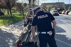 Policjant Wydziału Ruchu Drogowego Komendy Miejskiej Policji w Łodzi sprawdza sposób zabezpieczenia ładunku na przyczepie.