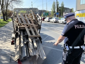 Policjant Wydziału Ruchu Drogowego Komendy Miejskiej Policji w Łodzi wskazuje na nieprawidłowo zabezpieczony ładunek.