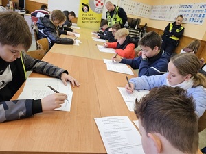 Uczestnicy turnieju piszą test wiedzy pod okiem policjantów.