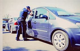 Umundurowany policjant zagląda do środka auta.