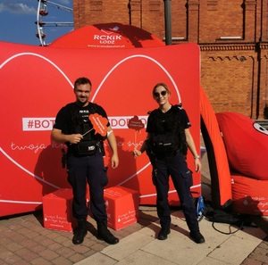 Umundurowani policjanci na tle banerów Regionalnego Centrum Krwiodawstwa i Krwiolecznictwa w Łodzi.