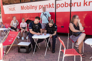 Umundurowani policjanci uzupełniają dokumenty przed pobraniem krwi.