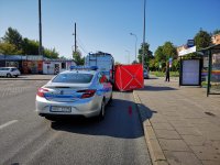 Na zdjęciu widzimy stojący radiowóz z Wydziału ruchu drogowego , w tle widać stojący czerwony parawan. Radiowóz stoi przy przystanku autobusowym.