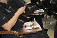 Na zdjęciu widoczny funkcjonariusz Służby Więziennej oglądający rekwizyty służące do zażywania środków odurzających.