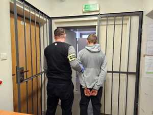 Policjant stoi z zatrzymanym mężczyzną.