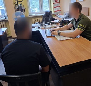 Nieumundurowany policjant przesłuchuje zatrzymanego mężczyznę.