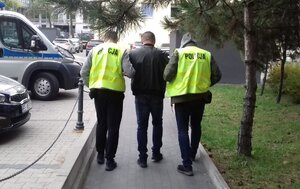 Policjanci prowadza zatrzymanego mężczyznę