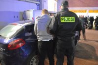 Zatrzymany mężczyzna za posiadanie środków pirotechnicznych prowadzony przez policjantów do radiowozu