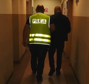 Policjant prowadzi zatrzymanego mężczynę