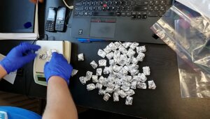 Policjant waży zabezpieczone środki psychoaktywne.