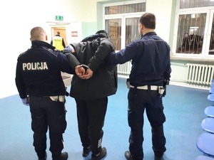 dwóch policjantów prowadzi zatrzymane4go pijanego kierowce