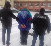 Na zdjęciu mężczyzna trzymany przez policjantów ubranych po cywilnego, w trakcie doprowadzania do budynku KMP w Łodzi.
