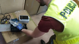 Policjant sprawdza sprzęt zabezpieczony w lombardzie.