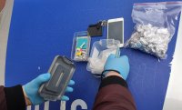 Policjant sprawdza zabezpieczone narkotyki i inne przedmioty znalezione przy zatrzymanym mężczyźnie