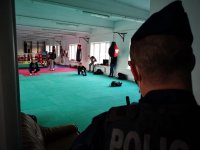 policjant przy wejściu na sale tre3ningów, w której widac kilku meżczyzn w strojach sportowych