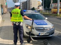 Na zdjęciu widzimy stojącego tyłem policjanta, który trzyma hulajnogę.