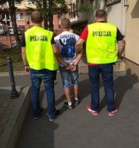 Policjanci prowadzą zatrzymanego sprawcę posiadania narkotyków