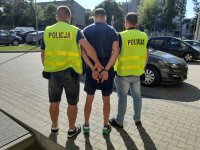 zatrzymany stoi na zewnątrz odwrócony tyłem z dwoma policjantami