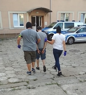 Policjanci prowadzą sprawce do komisariatu.