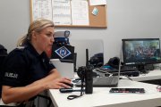 Policjantka ruchu drogowego siedzi przed komputerem, rozmawia z dziećmi uczestniczącymi w lekcji. Dzieci widać na ekranie stojącego na drugim planie komputera.