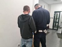 Umundurowany policjant ruchu drogowego pobiera odbitki linii papilarnych od nietrzeźwego kierującego