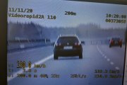 Na obrazku pokazano zdjęcie wideorejestratora , na który widać jadący ciemny samochód osobowy, obok jest zapisana prędkość 190 kilometrów na godzinę.