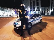 Policjant ruchu drogowego stoi przy oznakowanym radiowozie.