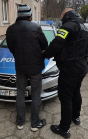 Policjant przygotowuje zatrzymanego do konwojowania