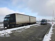 Samochód ciężarowy oraz oznakowany radiowóz stoją na parkingu.