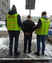 Policjanci prowadzą zatrzymanego mężczyznę.